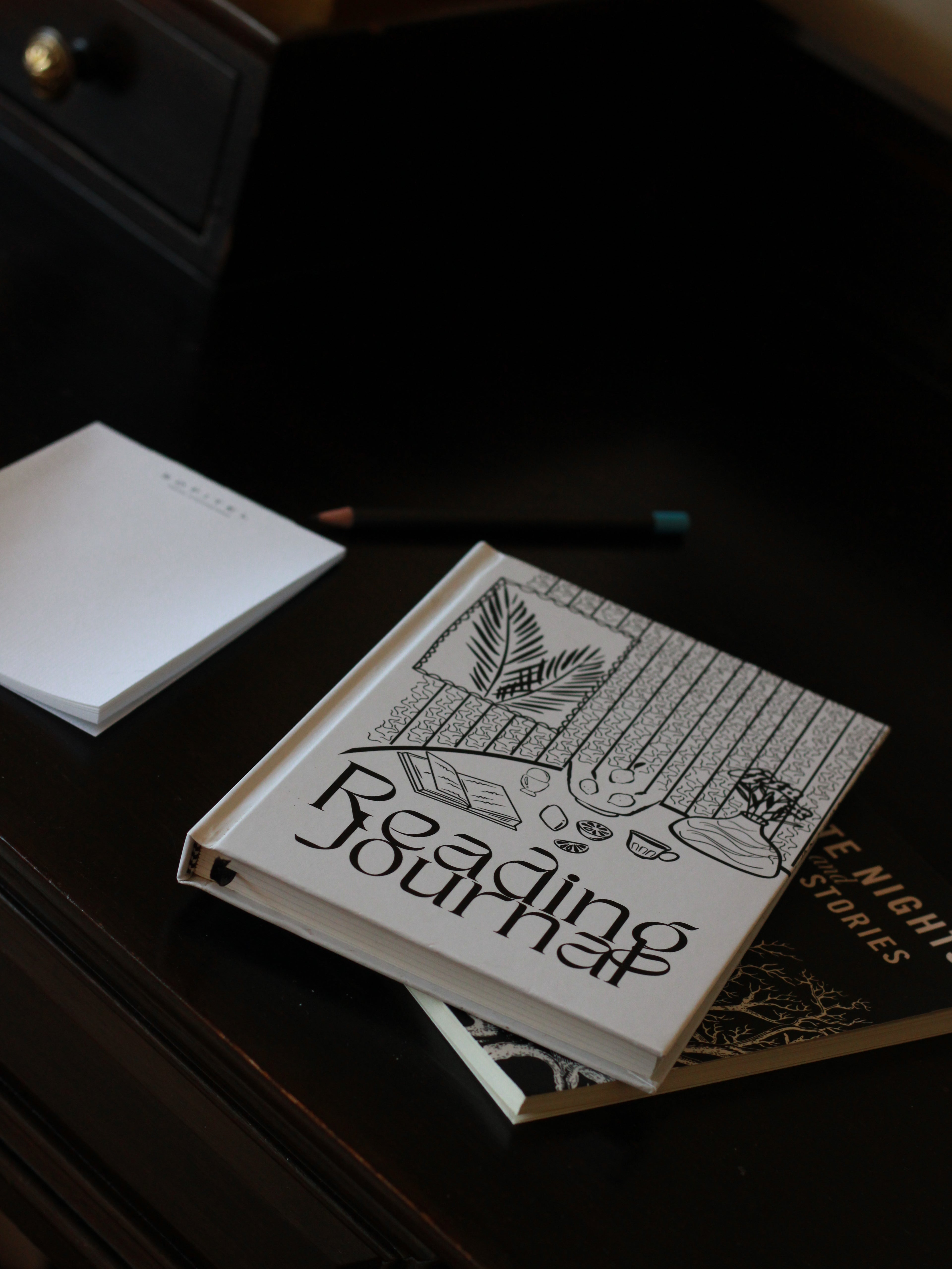 Book titled 'Reading Journal' with decorative cover on a dark surface